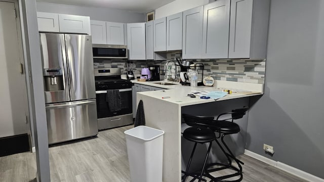 kitchen with backsplash, a breakfast bar, sink, and stainless steel appliances