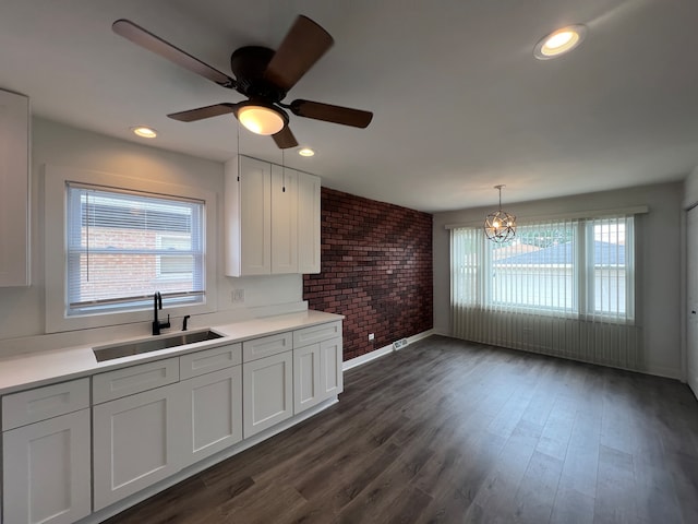 kitchen featuring a healthy amount of sunlight, white cabinetry, sink, and brick wall