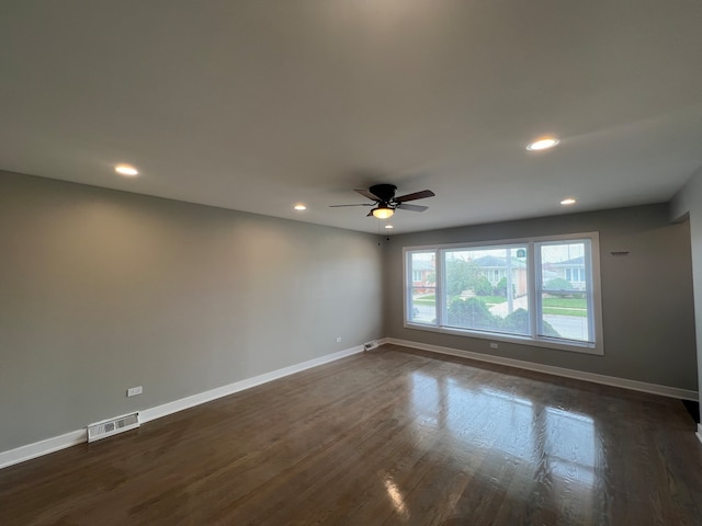 spare room with dark hardwood / wood-style flooring and ceiling fan