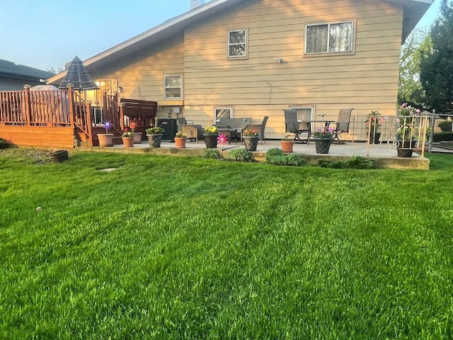 rear view of property featuring a lawn, a patio, and a wooden deck