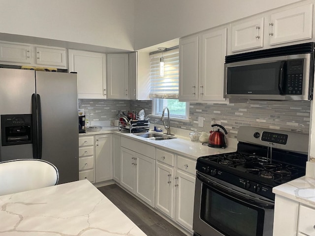 kitchen featuring white cabinetry, sink, stainless steel appliances, light stone counters, and decorative backsplash