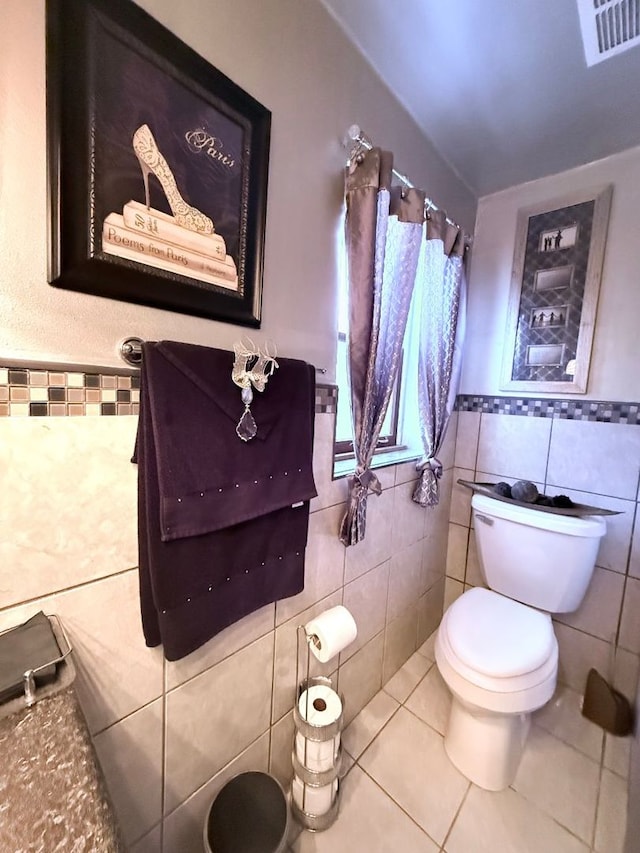 bathroom featuring tile patterned floors, toilet, and tile walls