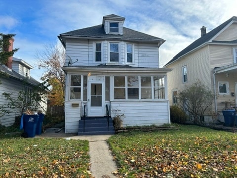 view of property with a sunroom and a front lawn