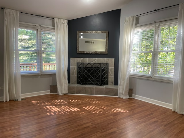 unfurnished living room featuring a fireplace, hardwood / wood-style floors, and a wealth of natural light