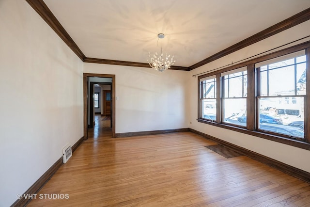 empty room featuring a notable chandelier, ornamental molding, and light hardwood / wood-style flooring