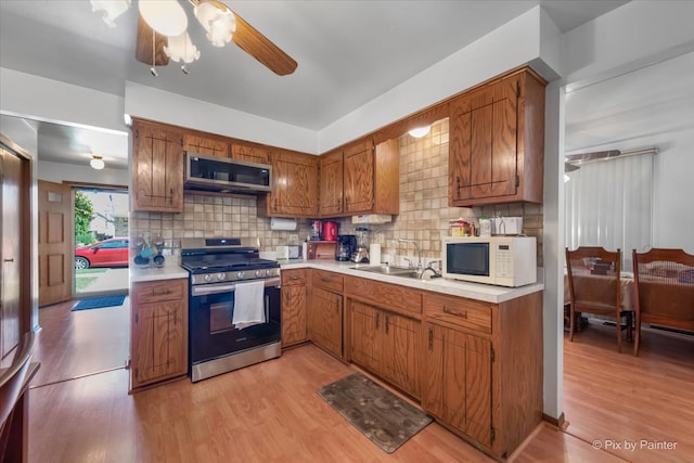 kitchen featuring decorative backsplash, stainless steel appliances, ceiling fan, sink, and light hardwood / wood-style flooring