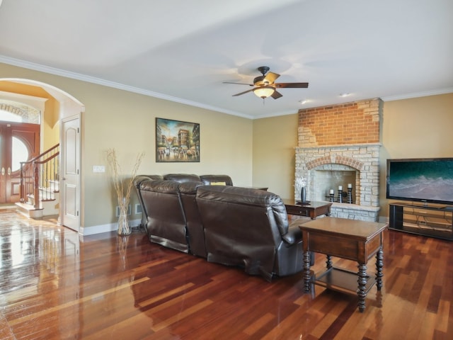 living room with a fireplace, dark hardwood / wood-style floors, ceiling fan, and crown molding