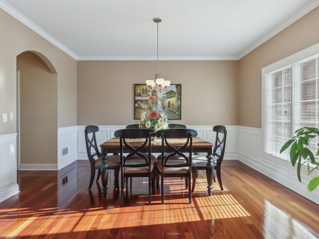 dining area featuring hardwood / wood-style flooring, an inviting chandelier, and crown molding