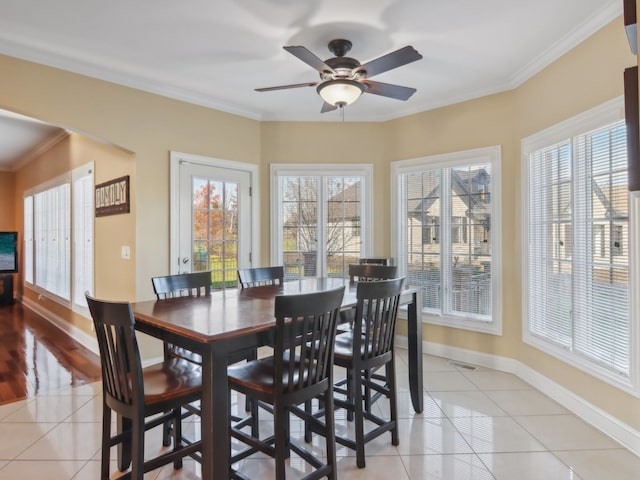 tiled dining area with ceiling fan and ornamental molding