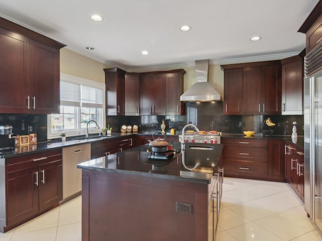 kitchen with sink, wall chimney exhaust hood, a kitchen island with sink, stainless steel appliances, and decorative backsplash