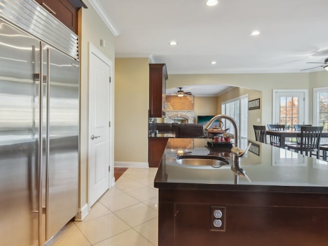 kitchen featuring sink, ornamental molding, an island with sink, and built in refrigerator