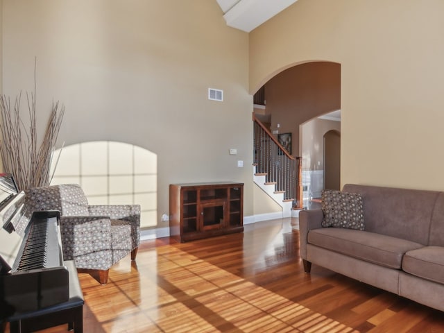 living room featuring a towering ceiling and hardwood / wood-style flooring