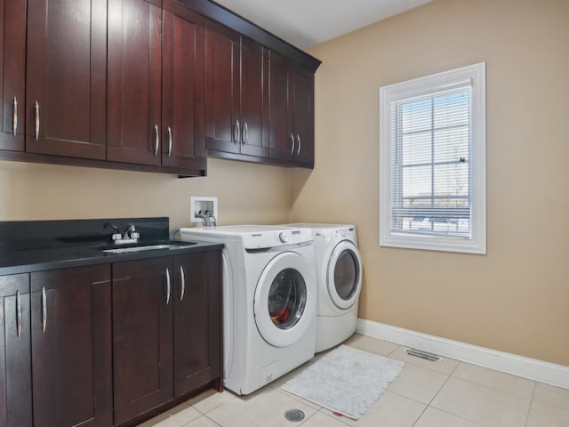 clothes washing area with separate washer and dryer, sink, light tile patterned flooring, and cabinets