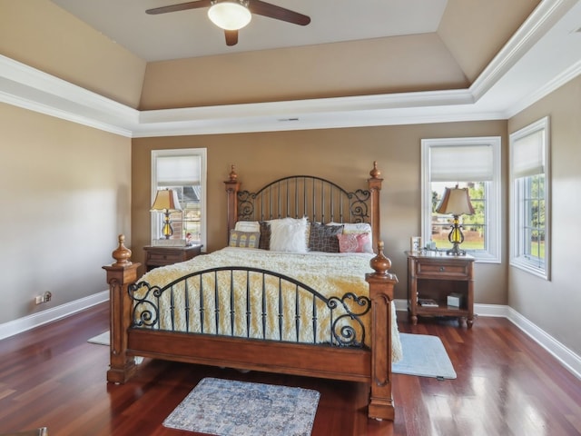 bedroom with ceiling fan, dark hardwood / wood-style flooring, crown molding, and a tray ceiling