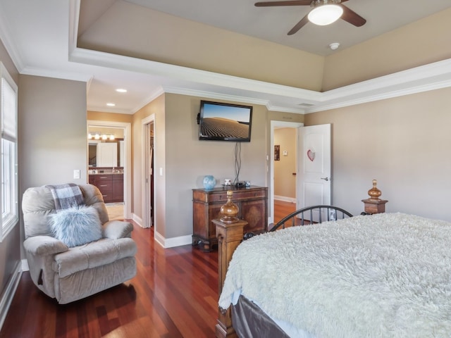 bedroom with dark wood-type flooring, ensuite bathroom, ceiling fan, ornamental molding, and a tray ceiling