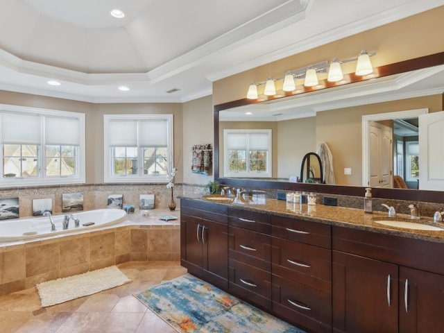 bathroom with vanity, a raised ceiling, crown molding, and tiled tub