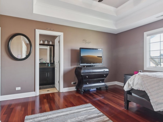 bedroom featuring wood-type flooring, connected bathroom, a tray ceiling, and crown molding