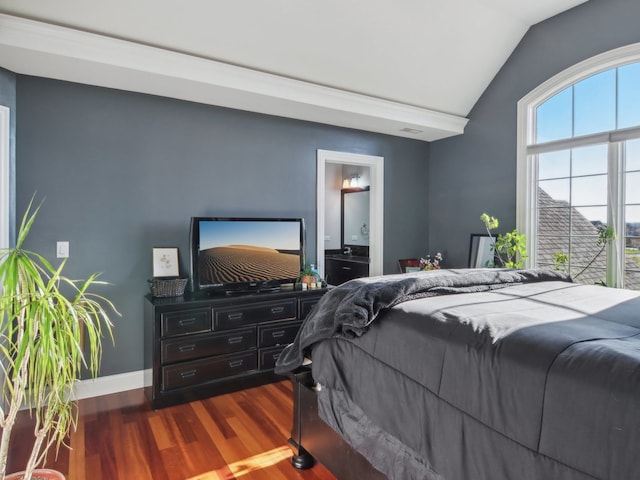 bedroom featuring dark hardwood / wood-style flooring, vaulted ceiling, and connected bathroom