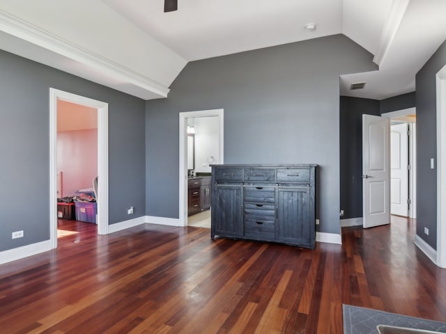 interior space featuring vaulted ceiling, dark wood-type flooring, and ensuite bath