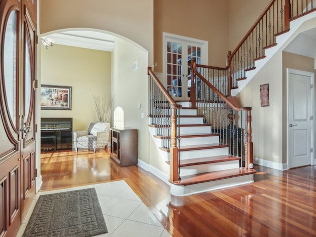 stairs with wood-type flooring, a towering ceiling, and french doors