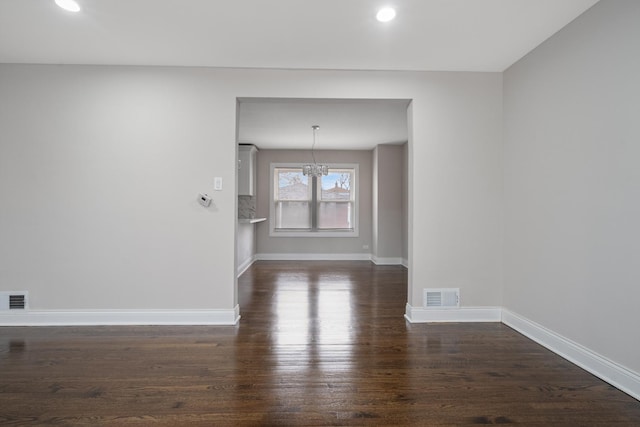 unfurnished room featuring dark hardwood / wood-style flooring and an inviting chandelier