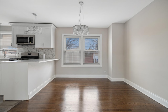 kitchen with appliances with stainless steel finishes, tasteful backsplash, pendant lighting, white cabinets, and dark hardwood / wood-style floors