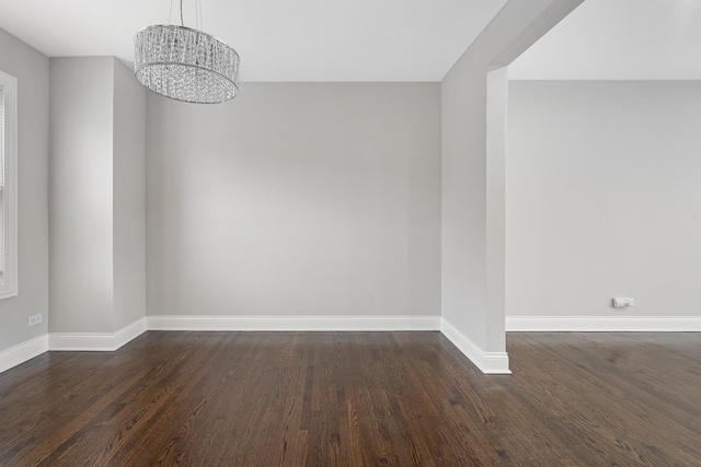 spare room with dark hardwood / wood-style flooring and a notable chandelier