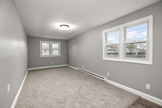 spare room with carpet flooring, a wealth of natural light, and a baseboard heating unit