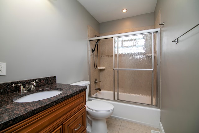 full bathroom with combined bath / shower with glass door, tile patterned floors, vanity, and toilet