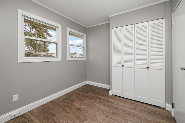 unfurnished bedroom featuring hardwood / wood-style flooring, crown molding, and a closet