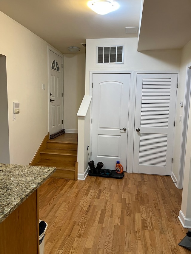 kitchen featuring sink, light hardwood / wood-style flooring, light stone countertops, and appliances with stainless steel finishes