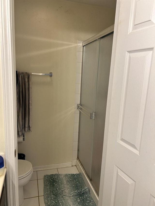 bathroom with a shower with door, tile patterned flooring, and toilet