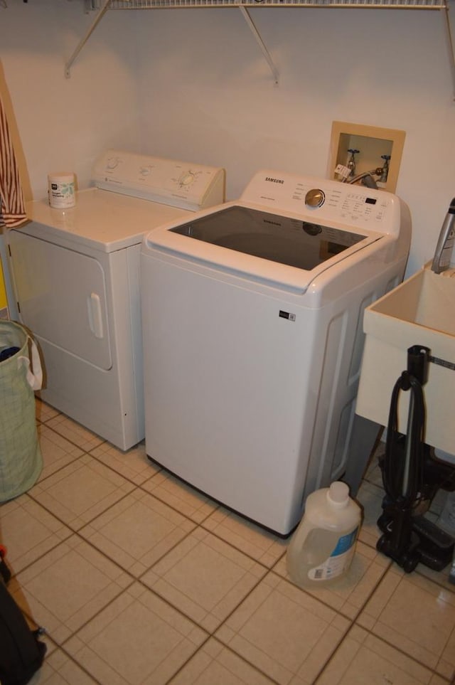 washroom with light tile patterned flooring, washing machine and clothes dryer, and sink