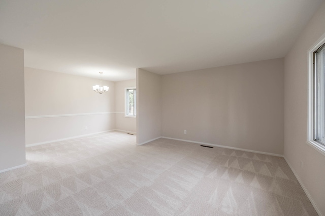 unfurnished room featuring light carpet and an inviting chandelier