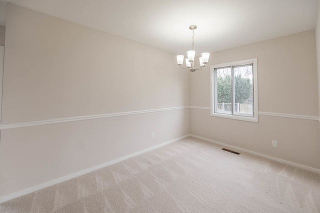 carpeted spare room featuring a chandelier