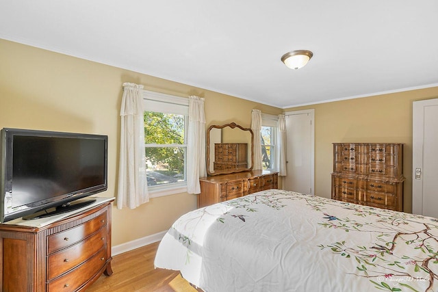 bedroom featuring baseboards, light wood-style floors, and ornamental molding