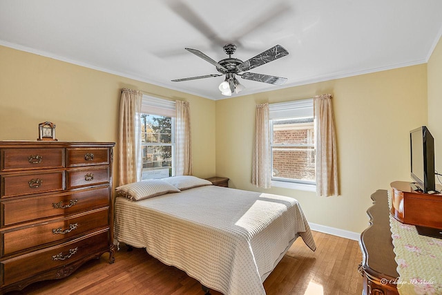 bedroom with multiple windows, wood finished floors, baseboards, and ornamental molding