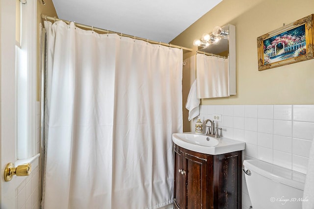 bathroom with toilet, tile walls, vanity, and a shower with curtain