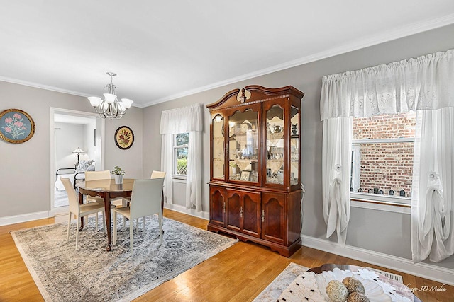 dining area with a notable chandelier, baseboards, light wood finished floors, and ornamental molding