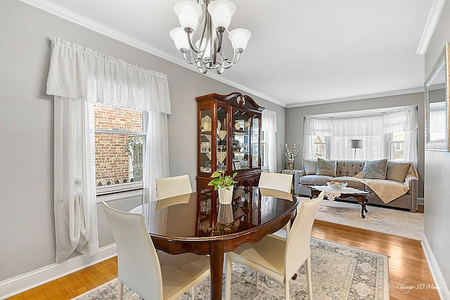 dining room with crown molding, light wood-type flooring, and an inviting chandelier