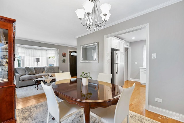 dining space with crown molding, baseboards, light wood finished floors, and a chandelier