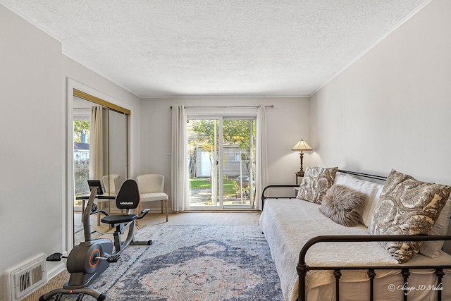 carpeted living room with visible vents, a textured ceiling, and ornamental molding