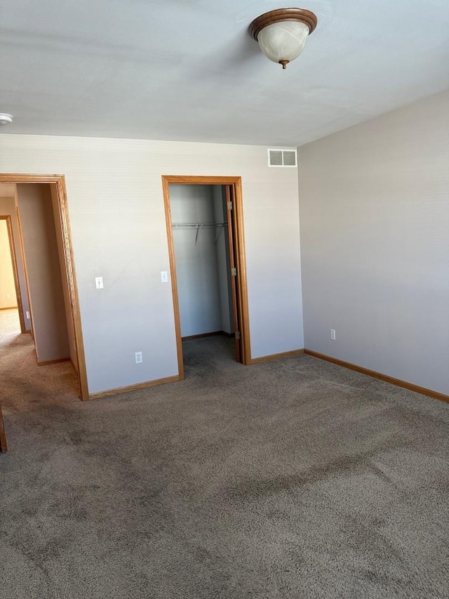 unfurnished bedroom with a walk in closet, carpet floors, and a closet