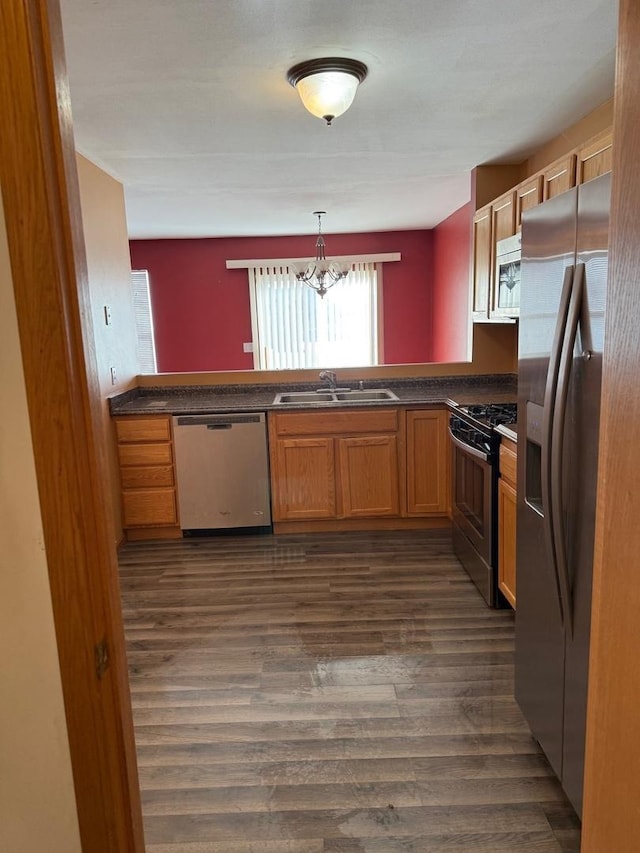 kitchen featuring kitchen peninsula, sink, decorative light fixtures, and appliances with stainless steel finishes