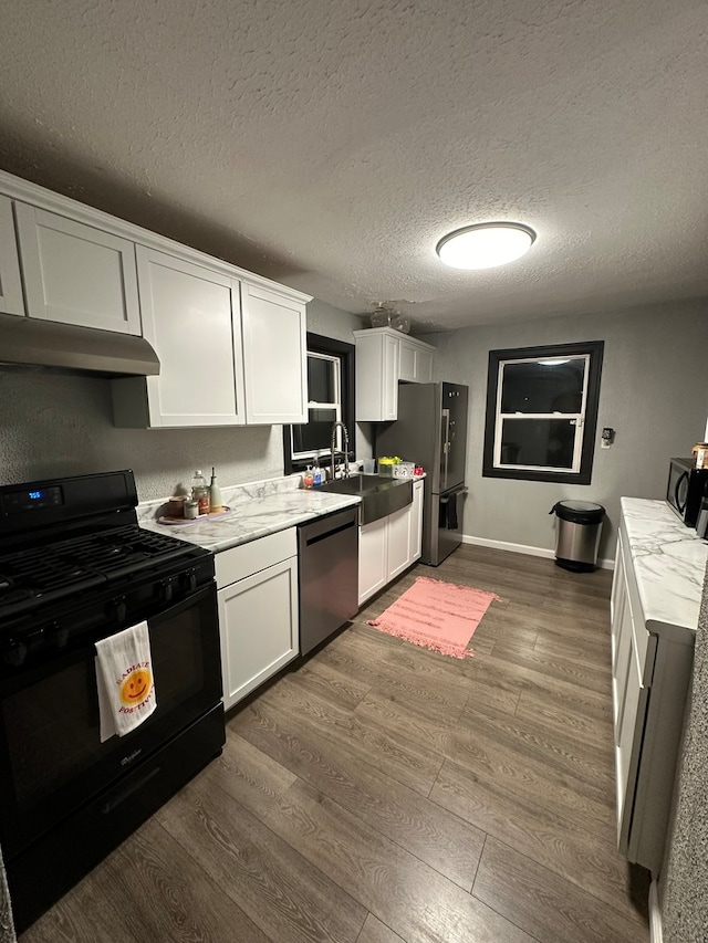 kitchen with a textured ceiling, stainless steel appliances, dark wood-type flooring, sink, and white cabinets