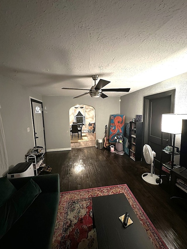 living room with ceiling fan, dark wood-type flooring, and a textured ceiling