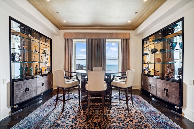 dining space with crown molding, a water view, and dark wood-type flooring