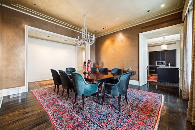 dining space featuring dark hardwood / wood-style flooring, crown molding, and an inviting chandelier