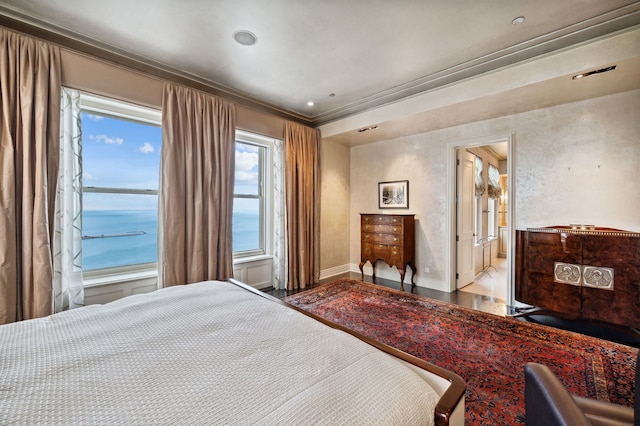 bedroom featuring hardwood / wood-style floors, ensuite bathroom, a water view, and crown molding