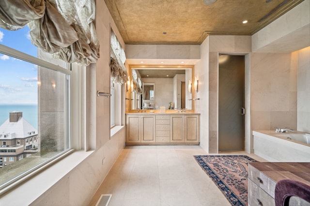 bathroom featuring vanity, a healthy amount of sunlight, a water view, and a bath